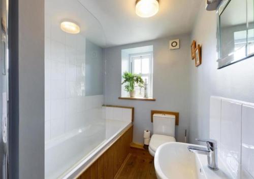 a white bathroom with a tub and a sink at Cringley Cottage in Askrigg