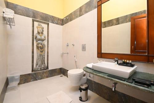 La salle de bains est pourvue d'un lavabo, de toilettes et d'un miroir. dans l'établissement Aaram Baagh Maheshwar, à Maheshwar