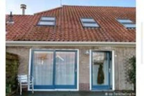 ein Haus mit einem Dach mit einer Katze im Fenster in der Unterkunft De Oostkamer; Eiland appartement naast natuurgebied Boschplaat in Oosterend
