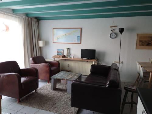 a living room with leather furniture and a blue ceiling at De Oostkamer; Eiland appartement naast natuurgebied Boschplaat in Oosterend