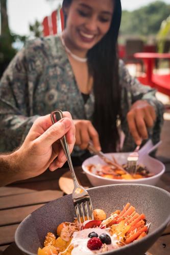 a woman sitting at a table with a plate of food at Villa Aikia (Adults Suites A/C) in Zipolite