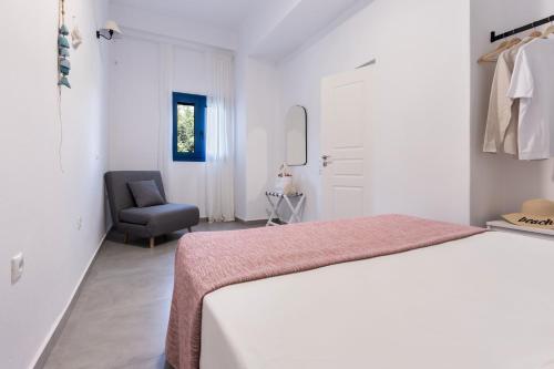 a white bedroom with a bed and a chair at Alasthas in Gavrion