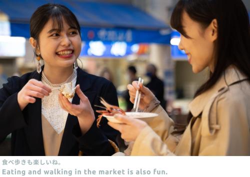 two women eating and walking in the market is also fun at LINNAS Kanazawa in Kanazawa