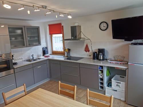 eine Küche mit grauen Schränken, einem Tisch und einer Uhr in der Unterkunft Haus Post in Todtnau