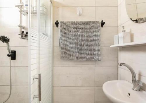 baño blanco con ducha y lavamanos en Central 1BR Oasis, Fast Fiber WiFi, Free Parking, Free Netflix with Shelter, en Haifa