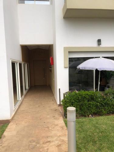 a white building with an umbrella in front of it at Résidence Kettani bouznika in Bouznika