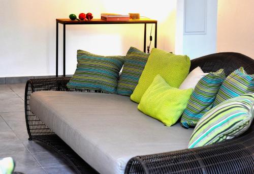 Un sofá de mimbre con almohadas coloridas. en Les Patios de Grands Bois, en Saint-Pierre