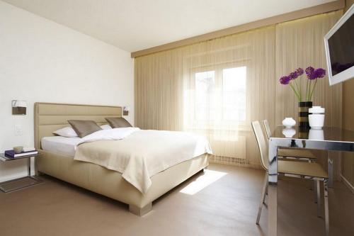 a bedroom with a bed and a desk and a window at VISIONAPARTMENTS Cramerstrasse 8-12 - contactless check-in in Zurich