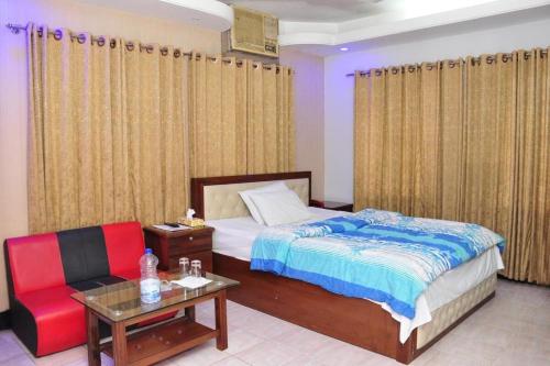 a bedroom with a bed and a chair and a table at Hotel Aero link Ltd in Dhaka