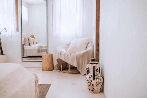 a white room with a chair and a mirror at Hotel Sages in Canggu