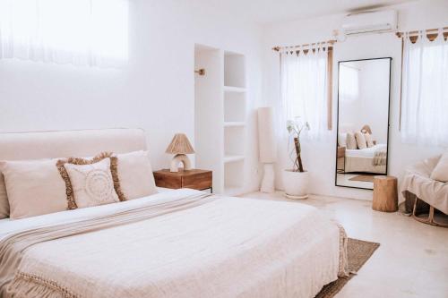 a white bedroom with a large bed and a mirror at Hotel Sages in Canggu