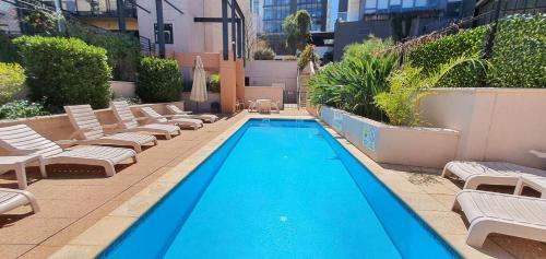 a pool with chaise lounge chairs and a swimming pool at Heart of the City 504 in Perth