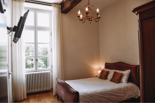 a bedroom with a bed and a chandelier and a window at Château de Mons Armagnac in Caussens