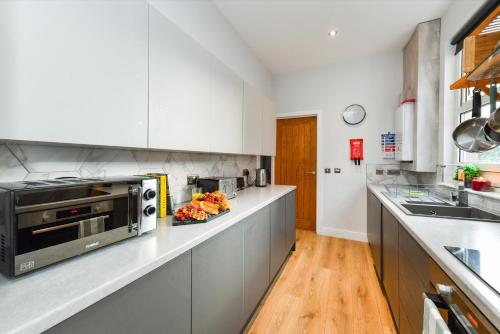 a kitchen with white cabinets and a microwave at Long Eaton Modern 4bed House in Long Eaton