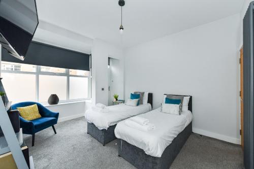 a bedroom with two beds and a blue chair at Long Eaton Modern 4bed House in Long Eaton