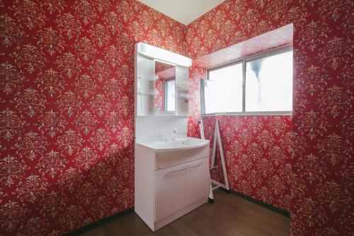 een badkamer met rood behang, een wastafel en een spiegel bij Bell-Rental Villa Engawa House in Fujikawaguchiko