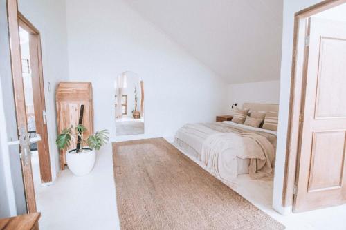 a white bedroom with a bed and a mirror at Hotel Sages in Canggu