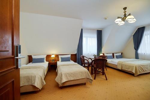 a hotel room with two beds and a table at Hotel Burkaty in Białka Tatrzanska