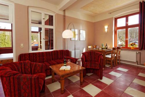 a living room with red chairs and a table and a dining room at Villa Maria Wohnung 05 in Ostseebad Koserow