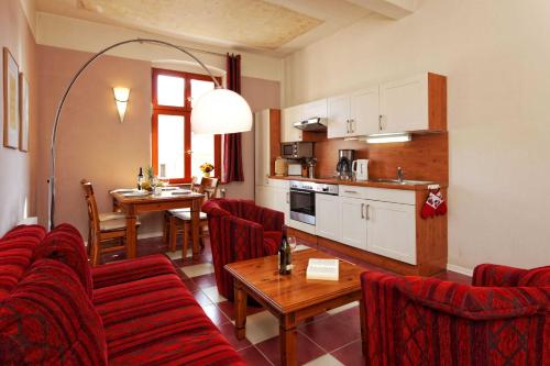 a kitchen and living room with red chairs and a table at Villa Maria Wohnung 05 in Ostseebad Koserow