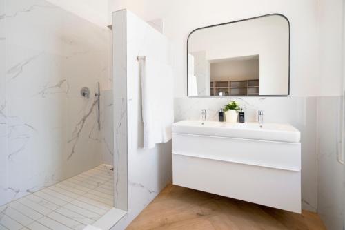 Baño blanco con lavabo y espejo en Middedorp Manor, en Stellenbosch