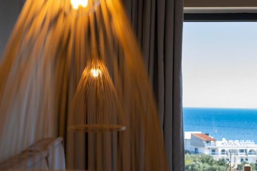 a chandelier hanging from a window with a view of the ocean at Meliti Hotel (Adults Only) in Agios Nikolaos