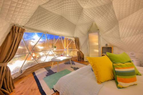 Pokój z łóżkiem i dużym oknem w obiekcie CAMP＆COTTAGE THE DOOR w mieście Fujikawaguchiko