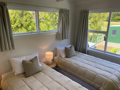 um quarto com 2 camas e 2 janelas em Sounds Good - Waikawa Holiday Home and Berth em Picton