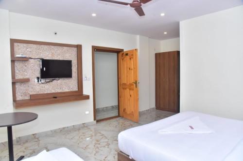 um quarto com uma cama e uma televisão na parede em hotel fortune sky em Bangalore