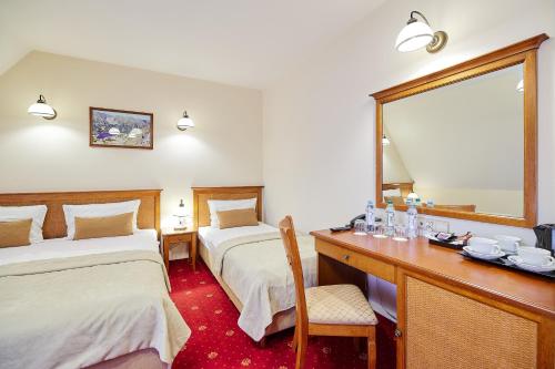 a hotel room with two beds and a desk with a mirror at Hotel Burkaty in Białka Tatrzanska