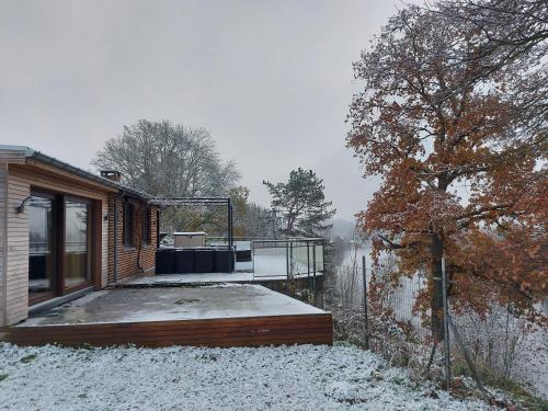a house with a deck in the snow at L'Éphém'Heer in Hastière-par-delà