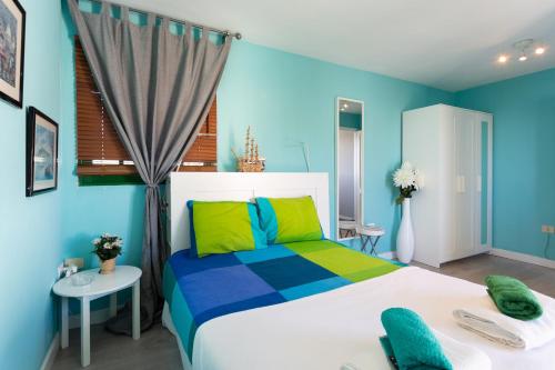 Dormitorio azul con cama blanca y almohadas coloridas en Home2Book Charming Sea Front House en El Escobonal
