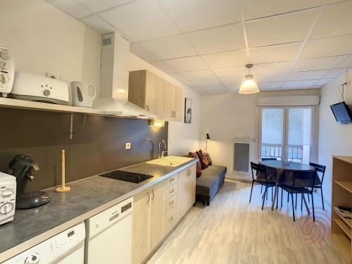 une cuisine et un salon avec une table et un canapé dans l'établissement Appartement F2 tout équipé avec balcons, ascenseur et Wi-Fi, proche des thermes de Lamalou - FR-1-451-141, à Lamalou-les-Bains