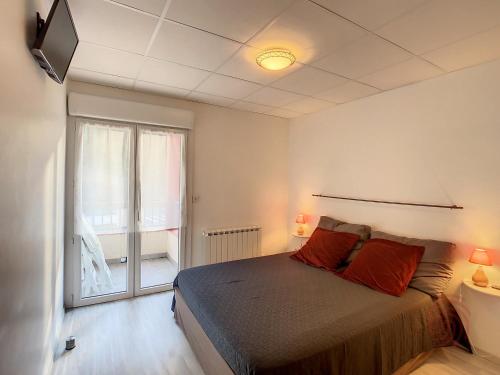 une chambre avec un lit et une grande fenêtre dans l'établissement Appartement F2 tout équipé avec balcons, ascenseur et Wi-Fi, proche des thermes de Lamalou - FR-1-451-141, à Lamalou-les-Bains