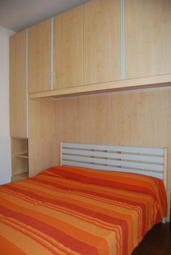 a bedroom with a bed with an orange blanket at Condominio San Michele in Bibione