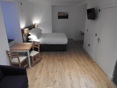 a small room with a bed and a table and a bed and a dining room at House of Juniper - Luxury Accessible Apartment in Broadford