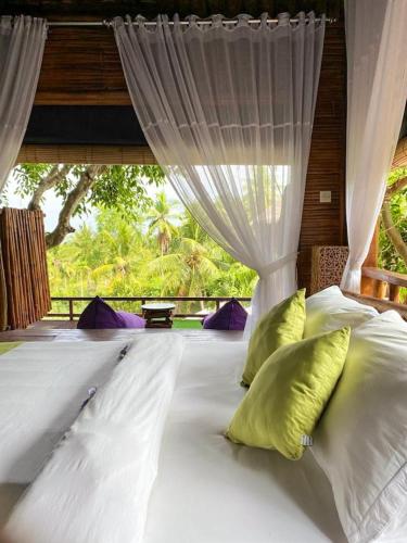 a bedroom with a bed with white sheets and pillows at Gading Tree House in Nusa Penida