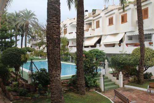 un hotel con piscina y palmeras en CASA ISA BEACH, 1 minute to the beach, en La Pobla de Farnals