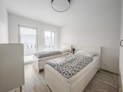 two beds in a white room with a window at Chalets New Apartmány Ivachnová in Ivachnová