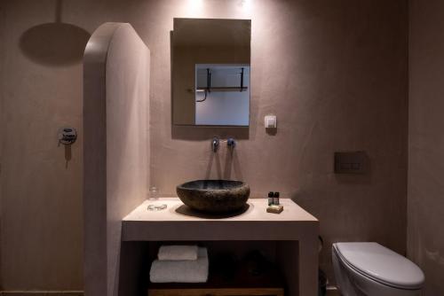 a bathroom with a sink and a toilet and a mirror at Meliti Hotel (Adults Only) in Agios Nikolaos