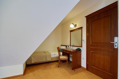 a bedroom with a bed and a desk with a mirror at Hotel Burkaty in Białka Tatrzanska
