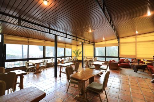 a restaurant with tables and chairs and windows at Pineland Hotel and Health Resort in Ḩammānā