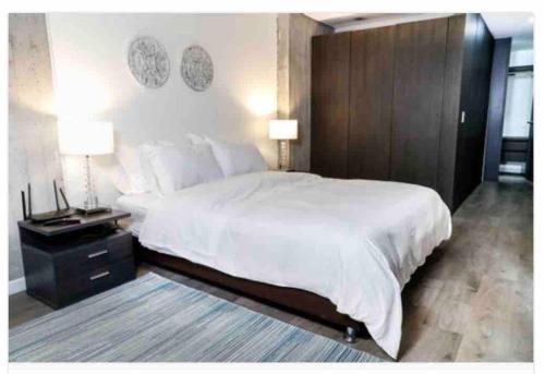 1 dormitorio con 1 cama blanca grande y 2 lámparas en Acogedor y amplio apartamento perfecta ubicacion! en Bogotá