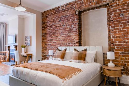 a bedroom with a brick wall and a bed at Oxford on Otho in Inverell