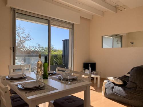 un salon avec une table avec une bouteille de vin dans l'établissement Magnifique T2 Duplex à Arcachon avec Terrasse, WiFi, à 100m de la Plage - FR-1-374-160, à Arcachon