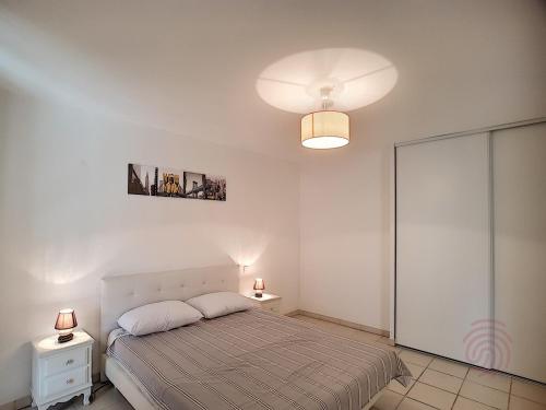 - une chambre avec un lit, deux tables et une lampe dans l'établissement Appartement F2 avec terrasse, clim, parking privé, proche centre-ville et thermes, animaux acceptés - FR-1-451-135, à Lamalou-les-Bains