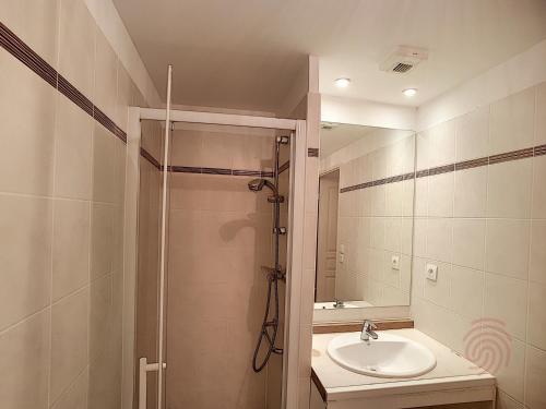 une salle de bain avec une douche, un lavabo et un miroir dans l'établissement Appartement F2 avec terrasse, clim, parking privé, proche centre-ville et thermes, animaux acceptés - FR-1-451-135, à Lamalou-les-Bains