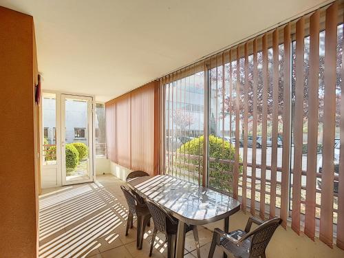 un balcon avec une table, des chaises et une fenêtre dans l'établissement Appartement F2 avec terrasse, clim, parking privé, proche centre-ville et thermes, animaux acceptés - FR-1-451-135, à Lamalou-les-Bains