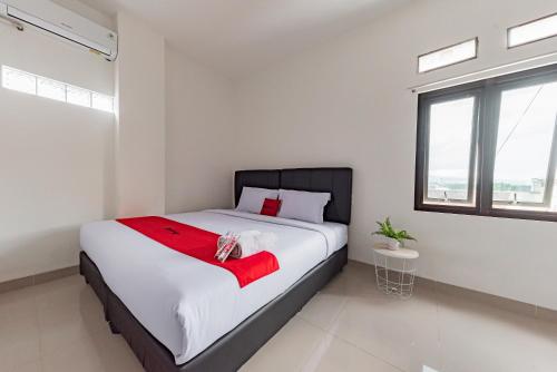 - une chambre avec un grand lit et une couverture rouge dans l'établissement RedDoorz @ Suryakencana Bogor, à Bogor