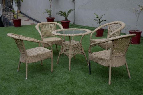 three wicker chairs and a table and chairs on grass at Hyphen Premier-Business Hotel in Meerut